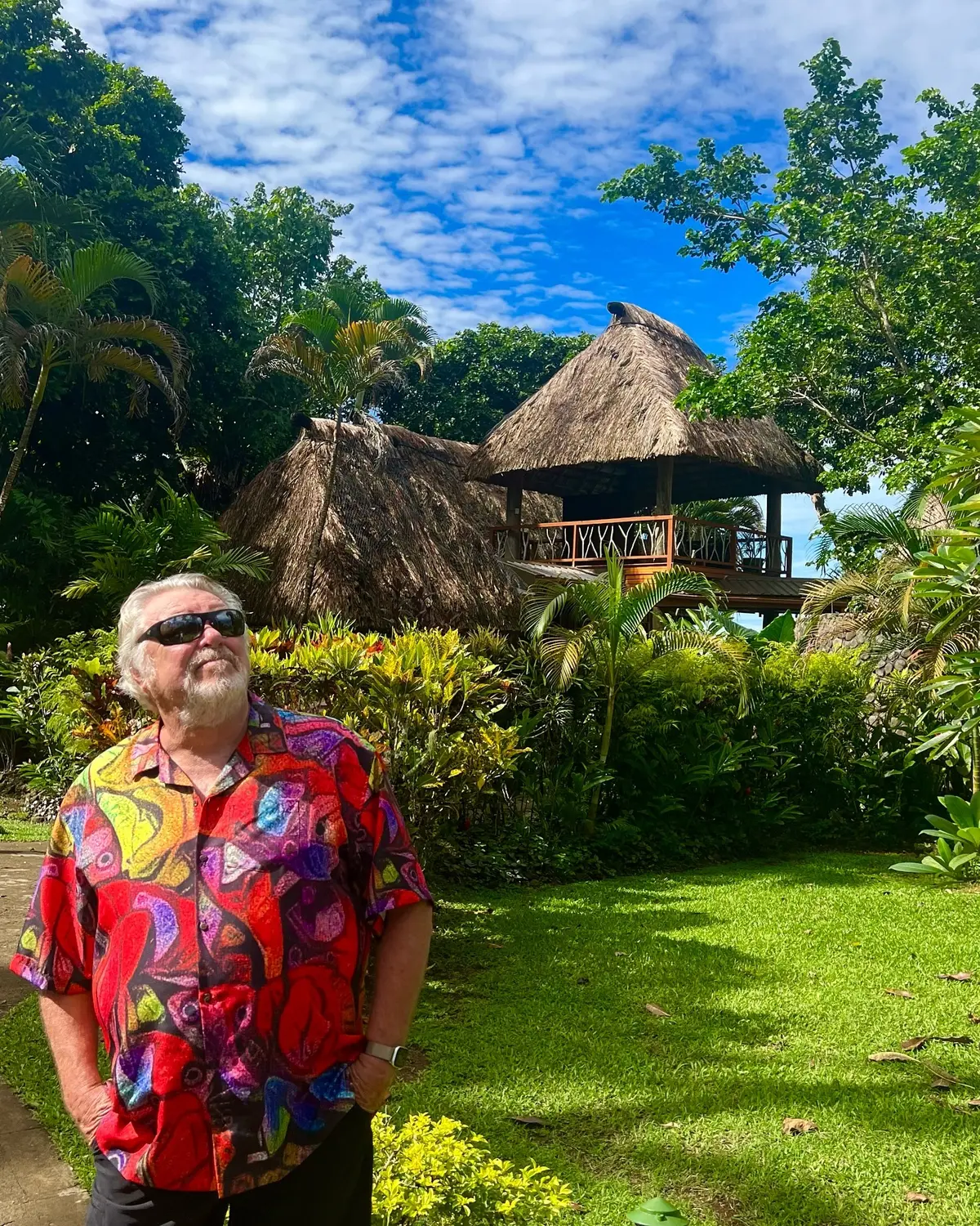 Walt Smith wearing one of his colorful designs in a tropical garden
